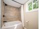 Shower and tub combination with stone-look tile, black fixtures, and a window providing natural light at 71 E Cove Ct, Cicero, IN 46034