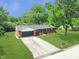 Aerial view of a brick house with an attached garage, green lawn and mature trees, surrounded by more greenery at 7234 Fairwood Dr, Indianapolis, IN 46256