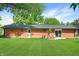Well-maintained backyard with lush green lawn and a charming red brick home with patio seating at 7234 Fairwood Dr, Indianapolis, IN 46256