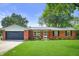 Charming brick home with well-manicured lawn, black shutters, an attached garage, and beautiful landscaping at 7234 Fairwood Dr, Indianapolis, IN 46256