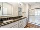 Bathroom featuring double vanity, dark granite countertops, white marble tiled shower, and modern fixtures at 830 Freeland Way, Carmel, IN 46032
