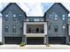 Well-maintained townhome featuring a covered balcony, dark garage doors, and a modern exterior design at 830 Freeland Way, Carmel, IN 46032