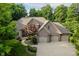 Aerial view showcases a brick home with a well-manicured lawn, curved walkway and mature trees at 9190 Hastings Trce, Indianapolis, IN 46234