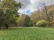 Picturesque backyard featuring lush green grass and mature trees in autumn colors under a partly cloudy sky at 9722 N Gasburg Rd, Mooresville, IN 46158