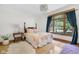A bedroom with hardwood floors, a patterned quilt on the bed, and a large window with blue drapes at 9722 N Gasburg Rd, Mooresville, IN 46158