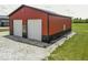 A red and black barn featuring two white roll up doors and gravel surrounding the structure at 10769 Shelbyville Rd, Indianapolis, IN 46259