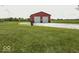 A red and black barn with two garage doors sits in a large green grassy field at 10769 Shelbyville Rd, Indianapolis, IN 46259