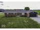 A brick home sits on a well-maintained lawn with manicured bushes and dark shutters at 10769 Shelbyville Rd, Indianapolis, IN 46259