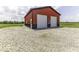 Exterior view of a modern outbuilding featuring two roll up doors and concrete apron at 10769 Shelbyville Rd, Indianapolis, IN 46259