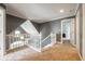 This hallway features an open staircase, carpet, and natural light at 11350 Old Stone Dr, Indianapolis, IN 46236