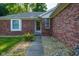 Charming brick home featuring a glass front door, decorative landscaping, and a well-manicured lawn at 12113 N Rooker Rd, Mooresville, IN 46158