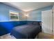 Blue bedroom with a comfortable queen bed, dark colored bedding, and a reading lamp at 1302 N Furman Ave, Indianapolis, IN 46214