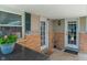 Inviting covered porch with brick accents, decorative plants, and 'Welcome to our Porch' sign at 1302 N Furman Ave, Indianapolis, IN 46214