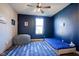 Bedroom featuring blue accent wall, blue rug, a window, and a ceiling fan for a comfortable space at 16235 Natures Way, Westfield, IN 46074