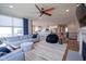 Bright and open living room area with a sectional sofa, ceiling fan, fireplace, and an open view to the kitchen at 16235 Natures Way, Westfield, IN 46074