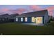 Exterior view of a home with a dark blue exterior, rear patio, and a lush green backyard at dusk at 216 Haywood Rd, Greenwood, IN 46142