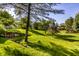 Backyard view showcasing the lush green lawn, mature trees, and retaining wall at 2247 Frisco Pl, Indianapolis, IN 46240