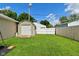 A serene backyard featuring a shed with a roll-up door, bordered by a wooden fence and lush green grass at 3059 Tansel Rd, Indianapolis, IN 46234
