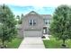Charming two-story home featuring a grey brick facade, two-car garage, and a well-manicured front yard with mature trees at 3075 W Crosscreek Dr, Monrovia, IN 46157