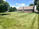 Expansive backyard with lush lawn, mature trees, deck, and brick exterior of the home at 3975 Keyway Dr, Greenwood, IN 46143