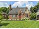Charming brick home featuring a well-manicured lawn, flowering bushes, and a classic red door at 5430 N Kenwood Ave, Indianapolis, IN 46208