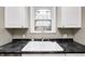Close-up of white cabinetry surrounding a sink with dark countertop and window at 5430 N Kenwood Ave, Indianapolis, IN 46208