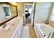 Well-lit bathroom featuring double sinks, a soaking tub, and a view into the bedroom at 5473 Forest Glen Dr, Brownsburg, IN 46112