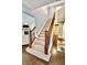 Well-lit staircase with carpeted steps and a dark wood banister, showcasing the home's design at 5473 Forest Glen Dr, Brownsburg, IN 46112