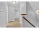 Upstairs hallway with neutral carpet, wood railing, and access to multiple rooms, providing a functional layout at 6329 Whitaker Farms Dr, Indianapolis, IN 46237
