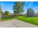 A spacious, well-manicured backyard features a concrete patio, lush green lawn, mature trees, and wood fencing at 7239 N Orchard Dr, Indianapolis, IN 46236