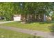 Brick home featuring a well-manicured lawn, two-car garage, and mature shade tree at 7239 N Orchard Dr, Indianapolis, IN 46236