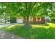 Charming brick home boasts a well-manicured front yard with a large tree and inviting curb appeal at 7239 N Orchard Dr, Indianapolis, IN 46236