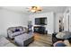 Comfortable living room featuring hardwood floors, ceiling fan, and ample seating with a large screen television at 7307 Twin Beech Dr, Indianapolis, IN 46226