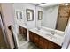 Bathroom featuring double vanity, large mirrors, and a door to hall at 7567 Muirfield Pl, Indianapolis, IN 46237