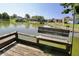 Dock with a weathered bench overlooks a serene lake, surrounded by lush trees and neighborhood homes at 7567 Muirfield Pl, Indianapolis, IN 46237