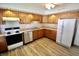 Bright kitchen with wood cabinets, stainless steel dishwasher, and laminate floors at 7567 Muirfield Pl, Indianapolis, IN 46237