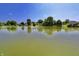 Expansive view of a tranquil lake surrounded by lush greenery and homes under a clear blue sky at 7567 Muirfield Pl, Indianapolis, IN 46237