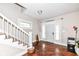 Bright entryway with hardwood floors, white staircase, and natural light streaming in from the front door at 806 N Gray St, Indianapolis, IN 46201