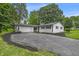 Charming white brick ranch-style home with attached garage and a large, resurfaced driveway and manicured landscaping at 8105 Allisonville Rd, Indianapolis, IN 46250