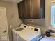 Bright laundry room featuring a side-by-side washer and dryer with storage at 8394 Glen Highlands Dr, Indianapolis, IN 46236