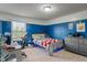 This blue bedroom includes a built-in desk, a dresser, and a large window at 8754 Lily Ct, Zionsville, IN 46077