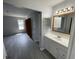 Bright bathroom featuring a modern vanity, large mirror, and gray flooring extending into the bedroom at 9458 Fordham St, Indianapolis, IN 46268