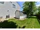 Green backyard featuring shed with white siding, dark roof, leafy tree, and partial view of the house at 10539 Ross Xing, Fishers, IN 46038