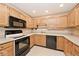 Well-lit kitchen with wood cabinets and black appliances, providing a practical cooking environment at 13 Marywood Dr, Greenfield, IN 46140