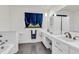 Bright bathroom featuring double sinks, tile floors, and vibrant blue curtains at 1340 Eustis Dr, Indianapolis, IN 46229