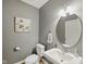 Cozy powder room featuring a modern sink, round mirror, and neutral wall color at 1680 Woodfield Dr, Greenwood, IN 46143