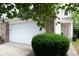 Attached two-car garage featuring brick accents, a white door, lush landscaping and a concrete driveway at 1856 Misty Lake Dr, Indianapolis, IN 46260