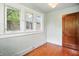 This bedroom features hardwood floors, three sunny windows, and a classic solid wood door at 39 N Bosart N Ave, Indianapolis, IN 46201
