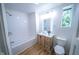 Modern bathroom features a wood vanity, framed mirror and tub with tile surround at 402 N Oxford St, Indianapolis, IN 46201