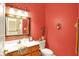 Powder room showcasing red walls, a decorative mirror, and a wood cabinet beneath the sink at 4704 Pearcrest Way, Greenwood, IN 46143
